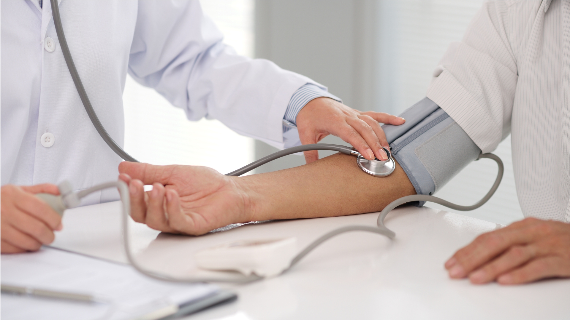 Doctor checking an older patient's blood pressure during a heart health check